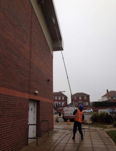 A picture of a member of the team cleaning a building. Ultra Cleaning Services provide jet washing and soft washing solutions to clean your whole building.