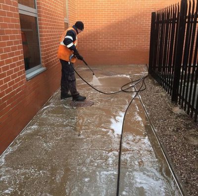 Picture of a member of the Ultra Cleaning Service team power washing a pathway - introducing playground cleaning services.